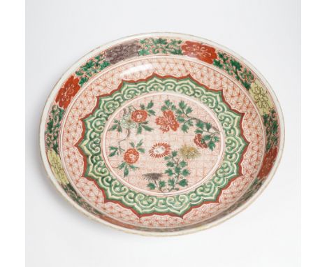 A Chinese famille verte dish, Kangxi period, decorated with flowers bands of brocade patterns, channel moulded foot, 33cm dia