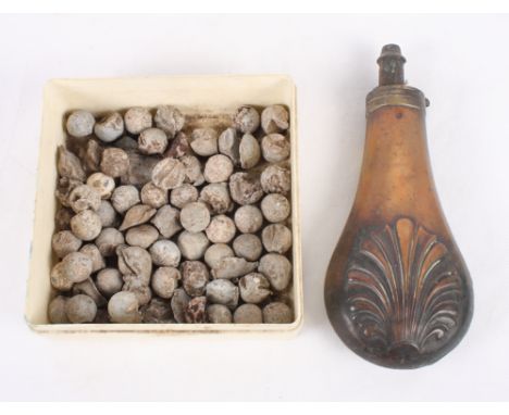 A collection of lead musket balls and a copper powder flask decorated shell