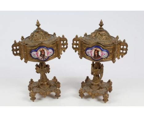 Pair of late 19th century French gilt metal pedestal urns and covers of Ecclesiastical Gothic form, the lower one with milita