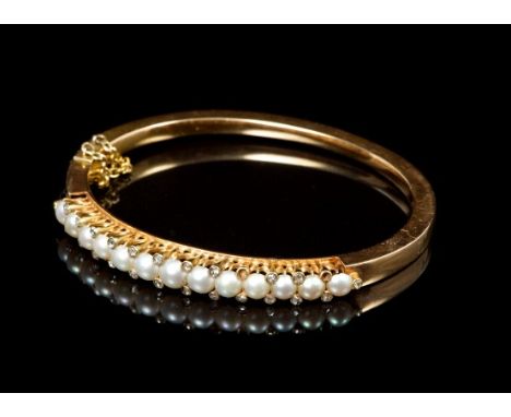 Victorian pearl and diamond bangle with a row of thirteen graduated half pearls, set with rose cut diamonds to the claws, in 