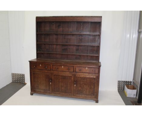 Early 19th century oak two height dresser with open shelves above, three drawers and two panelled doors below with turned han