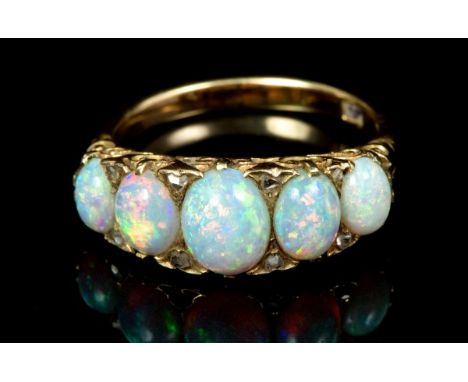 Edwardian gold opal five stone ring with five graduated oval opal cabochons in carved gold scroll setting with rose cut diamo