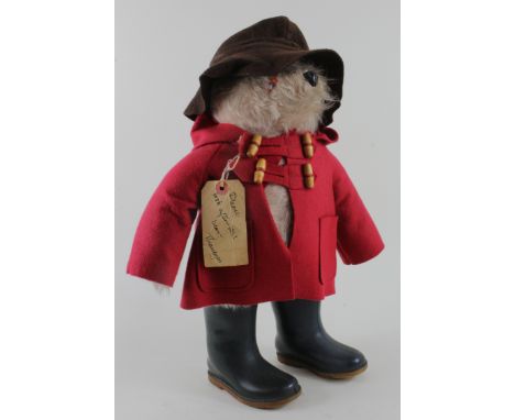 Paddington Bear by Gabrielle, red duffle coat, brown rain hat and black dunlop boots, with original luggage tag, height 48cm 