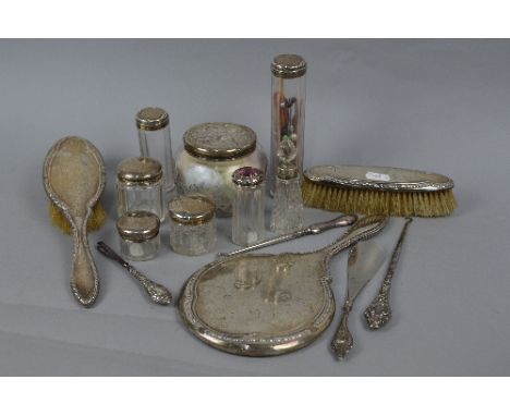 A QUANTITY OF SILVER BACKED AND TOPPED DRESSING TABLE AND MANICURE REQUISITES, includes a hand mirror, two brushes, a scent b