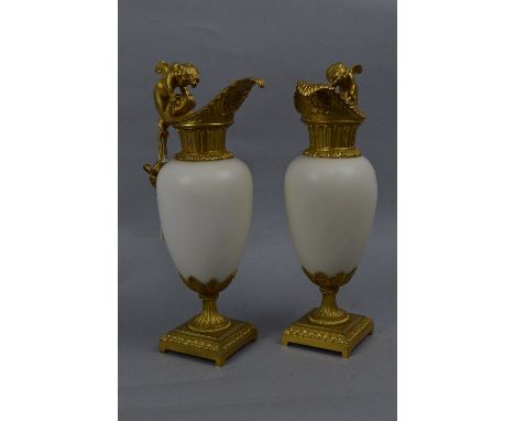 A PAIR OF CONTINENTAL ORMOLU AND WHITE MARBLE EWER MANTELPIECE ORNAMENTS, the handle cast as cherubs or merboys with the tail