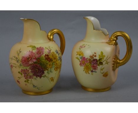 A PAIR OF ROYAL WORCESTER BLUSH IVORY FLATBACK JUGS, gilt handled, painted with cornflowers, forget me nots, chrysanthemums a