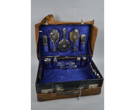 AN EDWARDIAN CROCODILE SKIN TRAVELLING TOILET CASE, with canvas outer cover, gilt initials to the case lid 'E.C.G', the inter