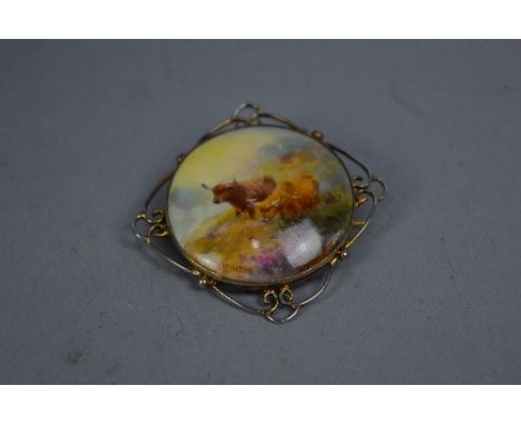 A ROYAL WORCESTER HARRY STINTON CIRCULAR PLAQUE BROOCH, decorated with two Highland Cattle in a landscape, signed in a gold p