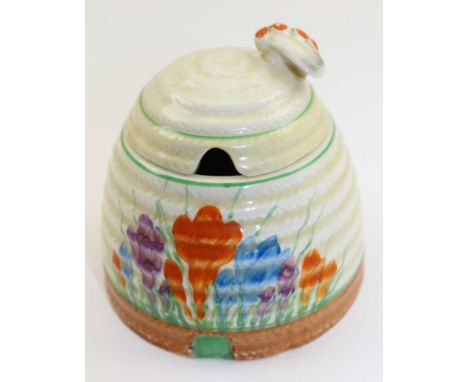 A CLARICE CLIFF CERAMIC BEE SKEP HONEY POT, the cover with moulded bee knop handle, the body painted in crocus pattern, print