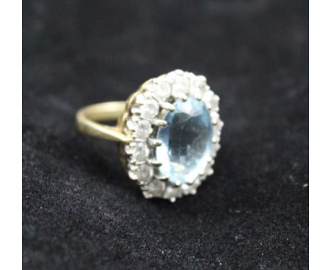 AN AQUAMARINE &amp; DIAMOND LADY'S RING, facet cut oval central stone surrounded by 14 brilliant cut diamonds, on an 18ct gol