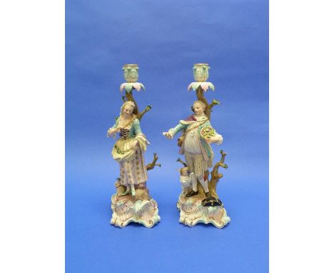 A pair of late 19thC Meissen large figural Candlesticks, modelled by Ernst August Leuteritz, she gathering fruit in her apron