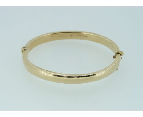A 9ct yellow gold hinged Bangle, the top engraved with scrolling foliate design, box snap, hallmarked Birmingham, 1992, safet