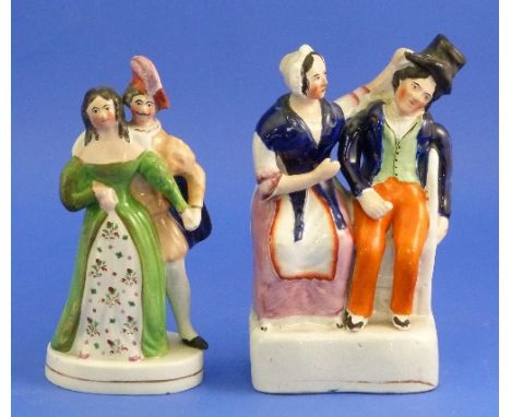A Staffordshire Pottery group of a seated man and woman quarrelling, decorated in colours, restored, 7½in (19cm) high, togeth