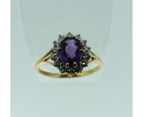 A cluster Ring, set with an oval amethyst, with fourteen small diamonds around, and mounted in 750 yellow gold, Size R.