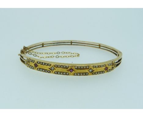 A hinged Bangle, formed of three strands of wirework with a plaque front, set with three small rubies and two diamonds and se