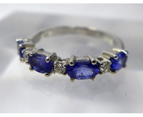 A 14ct white gold, diamond and tanzanite ring, alternately set with three round briliant-cut diamonds and four oval faceted t