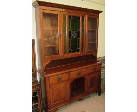 An Edwardian oak kitchen dresser, the moulded cornice above a leaded stained glass panel and a pair of glazed doors, the base
