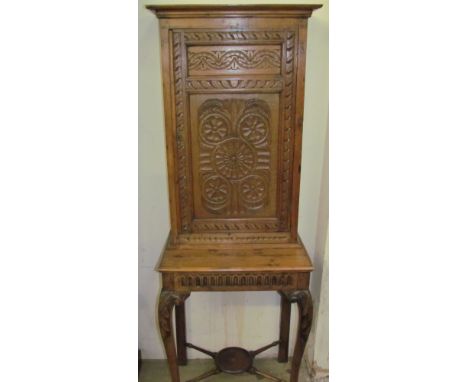 A 19th century oak side cabinet on stand, with carved panel door, the base with a carved frieze on leaf carved cabriole legs 