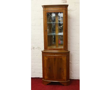 A yew wood corner display cupboard with mirrored interior and internal light.