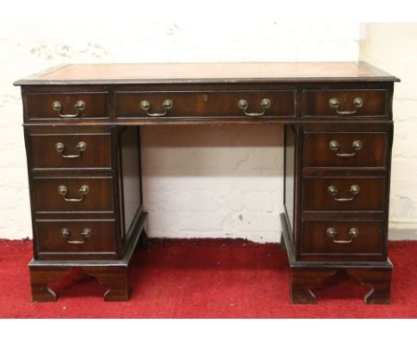 A mahogany and leather topped pedestal desk raised on bracket feet.