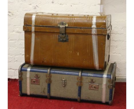 A tin travel trunk along with a canvas travel trunk.