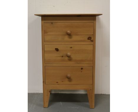 A pine three drawer bedside cabinet raised on bracket feet.