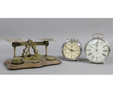 A set of antique walnut and brass postal scales and weights along with two alarm clocks.