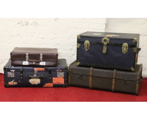A students wooden bound travel trunk along with two other travel trunks and a suitcase.
