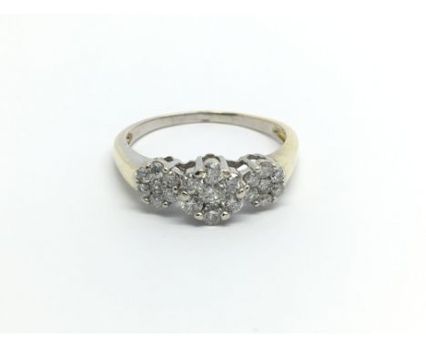 An unmarked gold ring set with a triple cluster of diamonds ring size V.