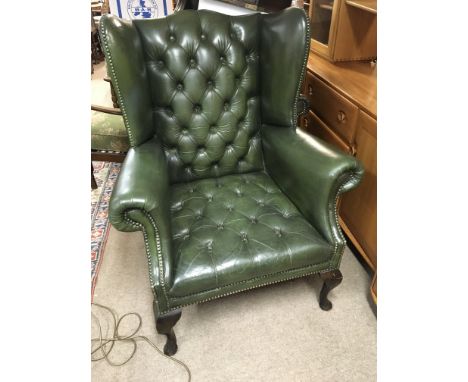 A Green leather button down back and seat wing arm chair.