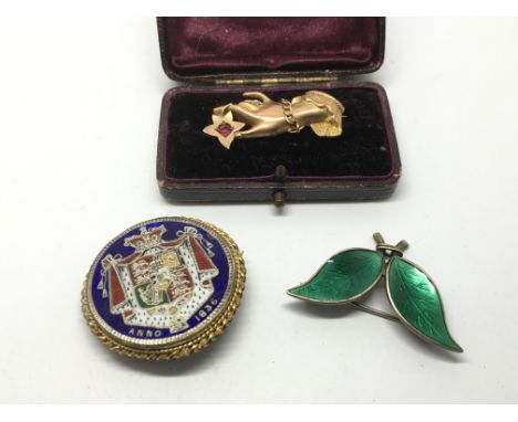 A 9ct gold brooch in the form of a ladies hand, an enamelled coin brooch and an enamel and silver Norwegian brooch in the for