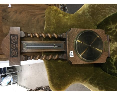 An oak barometer with barley twist supports and a brass dial