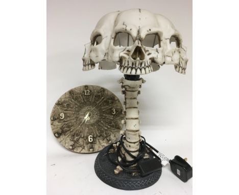 A lamp in the form of skulls and a spine (height 37cm approx), together with a Battery operated clock decorated in skeletons 