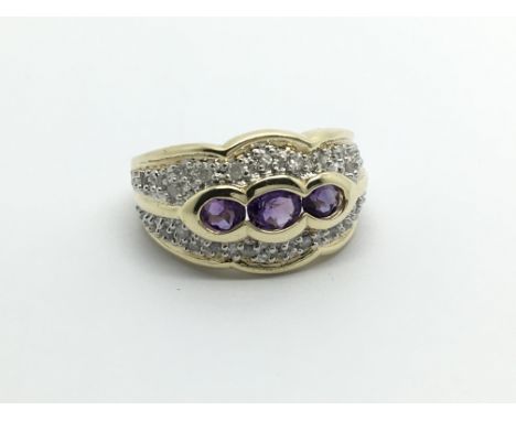 A 9carat gold ring set with three amethyst with a pattern of diamonds ring size N.