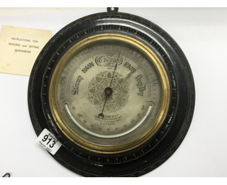 An Early 20th century round shaped oak cased wall barometer with a silvered ornate engraved dial. Maker Newton &amp; Co Londo