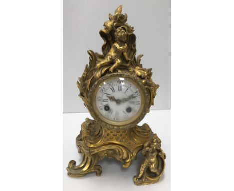 A 19th Century French gilt brass cased mantel clock in the Rococo taste with putti decoration amongst shells and flowers and 