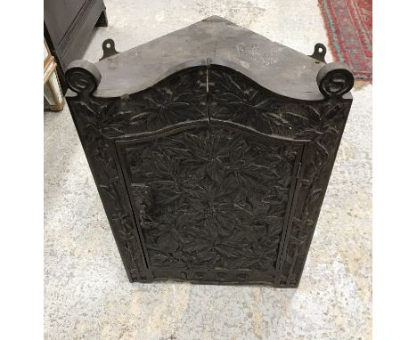 An Edwardian carved oak hanging corner cupboard in the Arts & Crafts style, with all over foliate and berry carved decoration