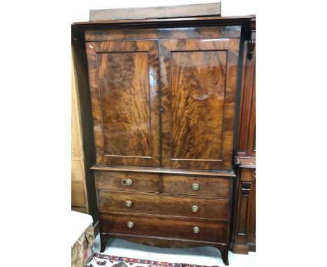 A Victorian figured mahogany linen press, the shallow cornice over a plain frieze and two panelled cupboard doors enclosing f