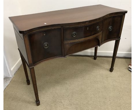 An Edwardian mahogany serpentine fronted sideboard, the two drawers flanked by deep drawer and cupboard door, on square taper