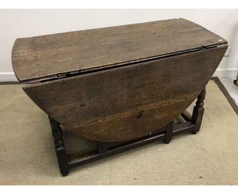 An oak oval gate-leg drop-leaf dining table in the 17th Century manner, the plain top over a plain frieze on turned and ringe