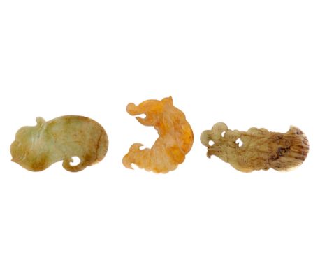 THREE CHINESE ARCHAIC STYLE HARDSTONE AMULETS, possibly jade, two carved each as a dragon fish, 8.5cm and 10.5cm long, the th