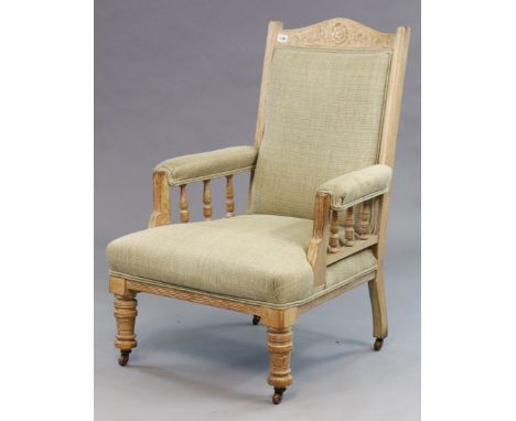 A Victorian carved oak frame armchair having a padded seat back &amp; arms, upholstered cream material, &amp; on short ring-t