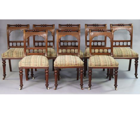 A set of eight Victorian mahogany dining chairs each with a spindle-rail to the open back, having a padded seat, &amp; on tur