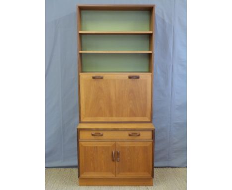 A retro G plan bookcase with fall flap bureau door opening to reveal a fitted interior above a single drawer and twin door cu