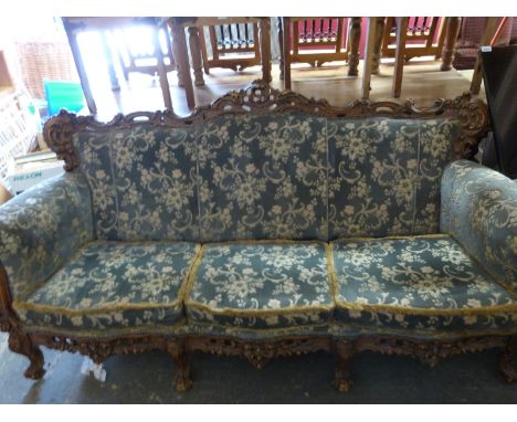 A large eight legged sofa with carved frame and two matching chairs