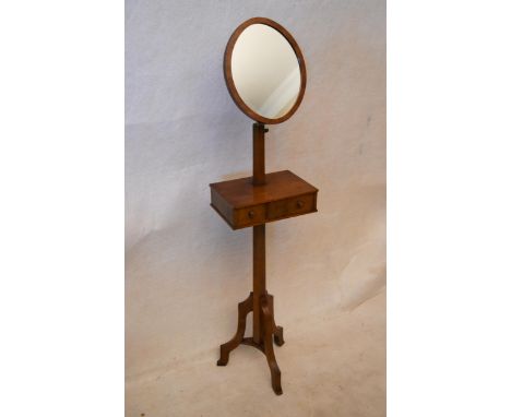 An early 20th century oak gentleman's shaving stand, with an oval mirror on a telescopic frame, the rectangular shelf contain