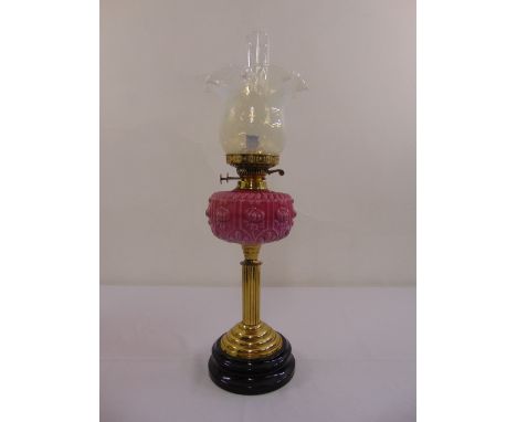 A pink glass oil lamp, ribbed cylindrical stem on stepped circular base