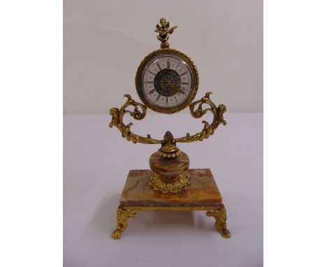 A continental gilt metal and agate mantle clock, the circular dial supported by leaf and scroll work and surmounted by a putt
