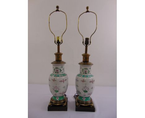 A pair of Chinese lamp bases, ovoid form decorated with flowers, leaves and scrolls on raised gilt metal bases