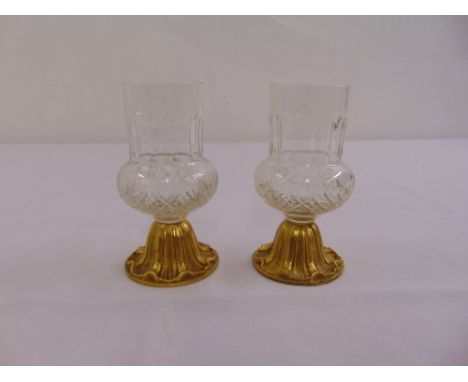 A pair of thistle shaped tea light holders on raised circular gilded metal bases